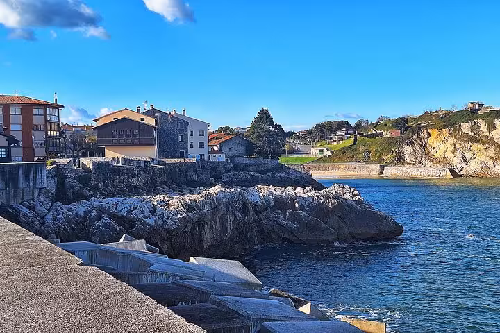 Scenic rocky coastline of Llanes with historic buildings and vibrant blue sea in Eastern Asturias.