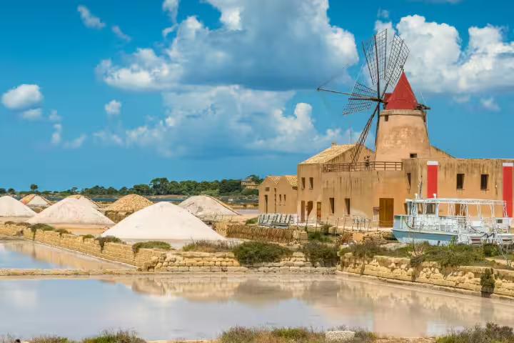 Historic windmill and white salt piles reflected in the Lo Stagnone saltpans near Mothia Island on a private tour from Palermo