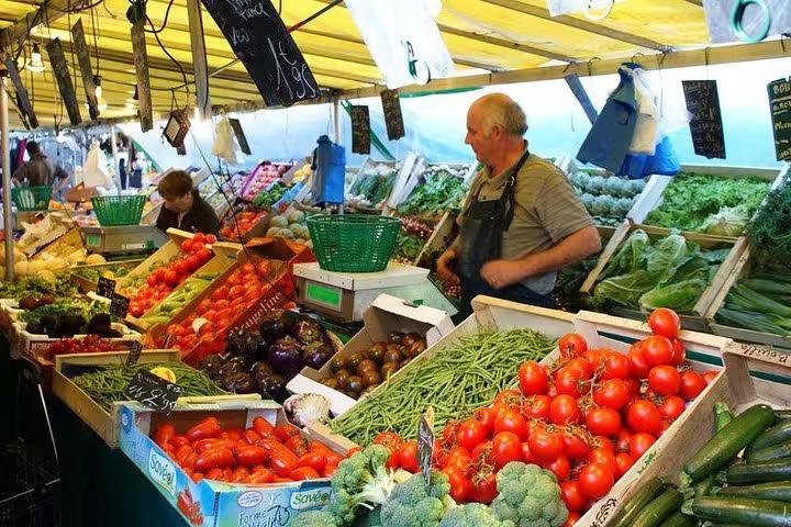 Vibrant vegetable stalls with fresh produce at a bustling local market near the Marais, ideal for a walking food tour.