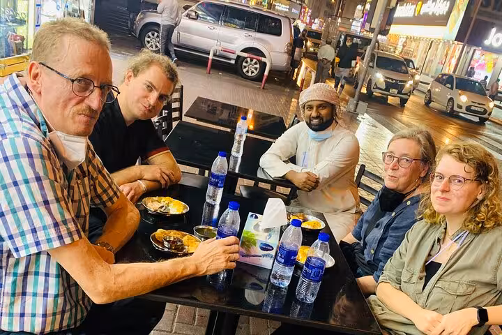 Small group dining on local Emirati snacks during Old Dubai food tasting walking tour in Deira