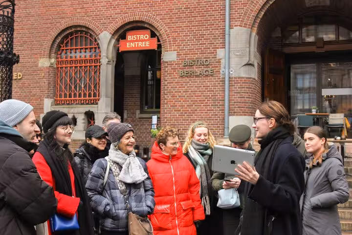 Local guide briefing a small group outside a brick building during a private city walking experience in Amsterdam