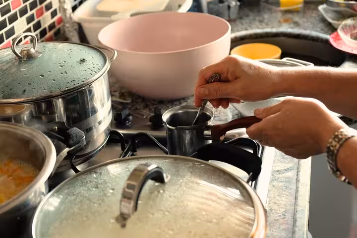 Local mom stirring Turkish coffee on the stove in a private Turkish cuisine cooking class in a home kitchen