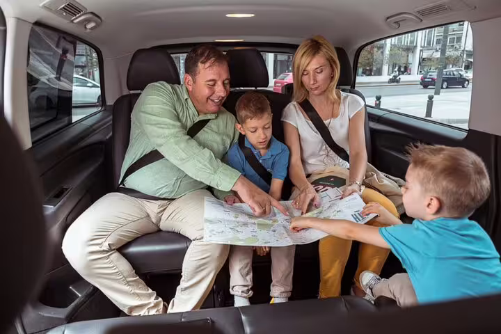 Family planning their Cotswolds day trip from London inside a private car, reading map between villages