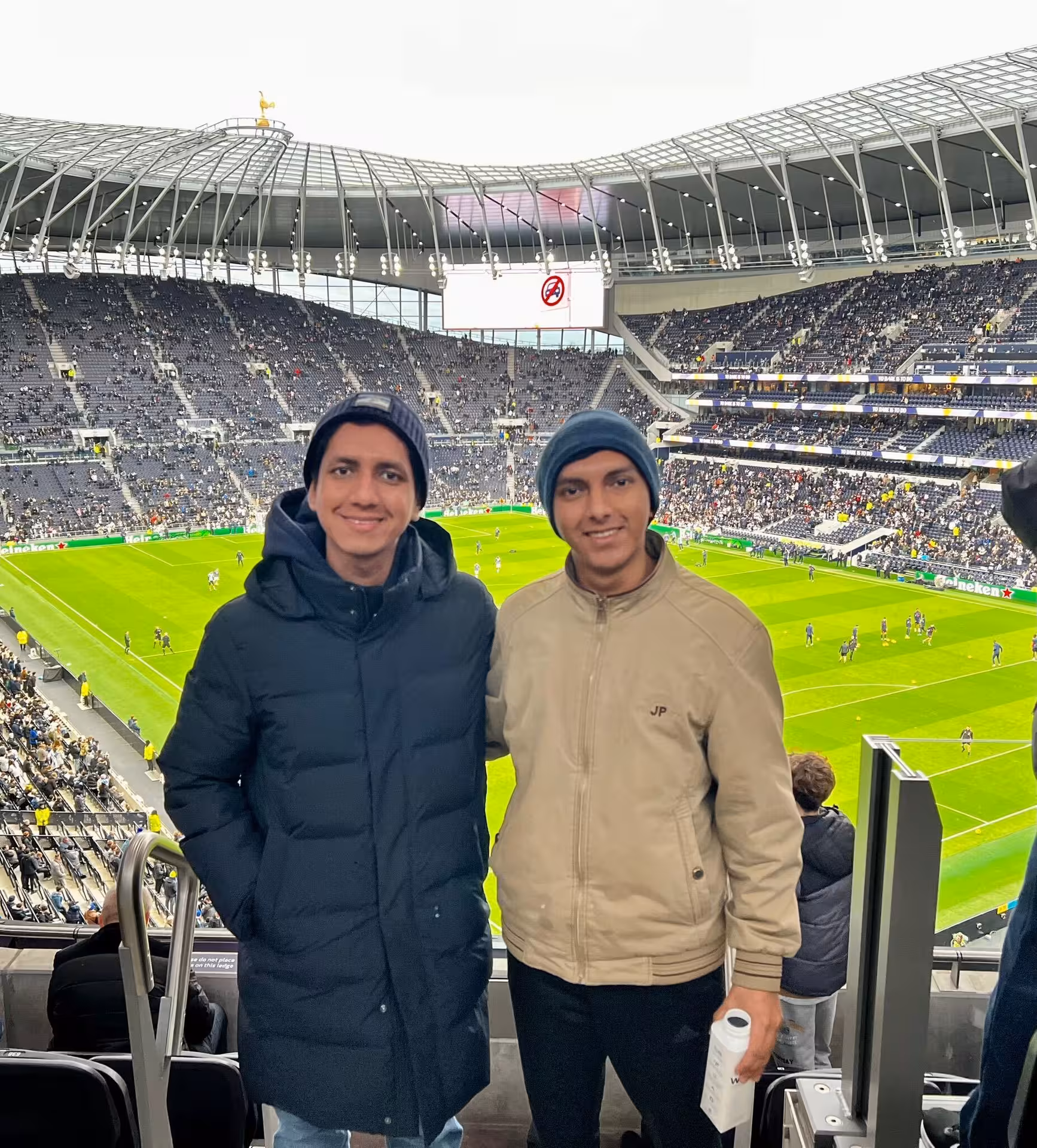 Friends enjoying a London football game with a local in a Premier League stadium, panoramic pitch and crowd view