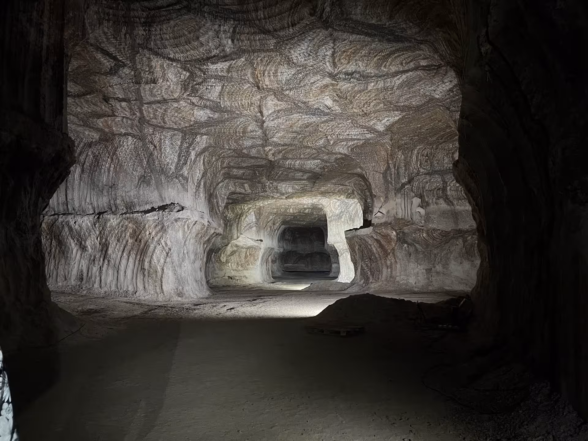 Dimly lit chamber in the Loulé rocksalt mine, highlighting intricate salt striations and spacious passageways.