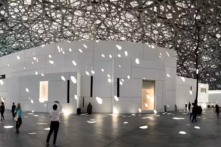 Louvre Abu Dhabi dome interior with sunlit patterns, highlight stop on private full-day Abu Dhabi city tour
