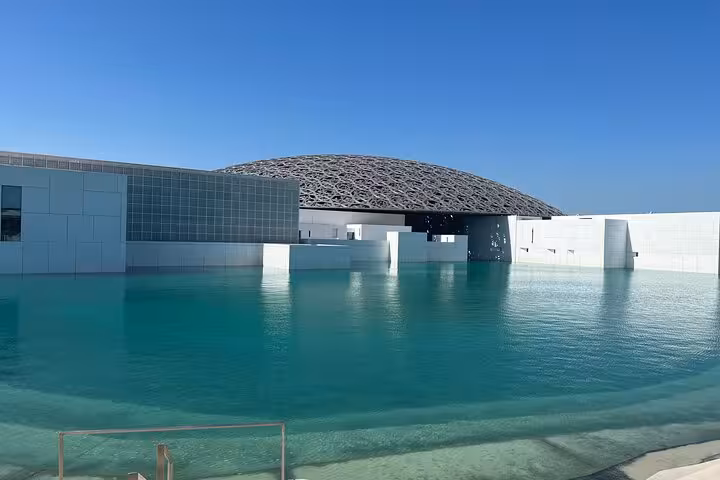 Louvre Abu Dhabi dome and turquoise lagoon view, cultural highlight on private Abu Dhabi tour with guide