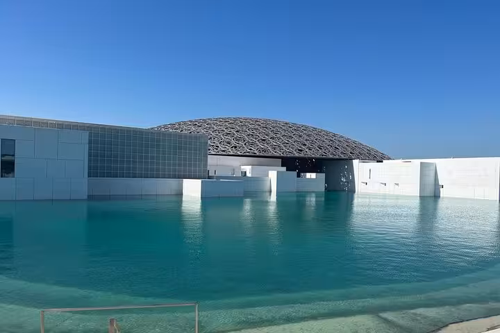 Louvre Abu Dhabi dome over turquoise water, must-see on Abu Dhabi layover sightseeing tour with airport transfer