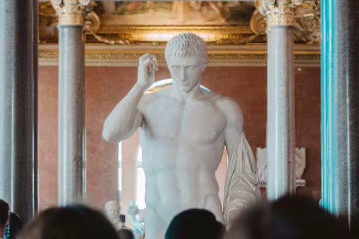 Visitors admire a classical marble statue at the Louvre, highlighting the museum's rich art collection and cultural tours.