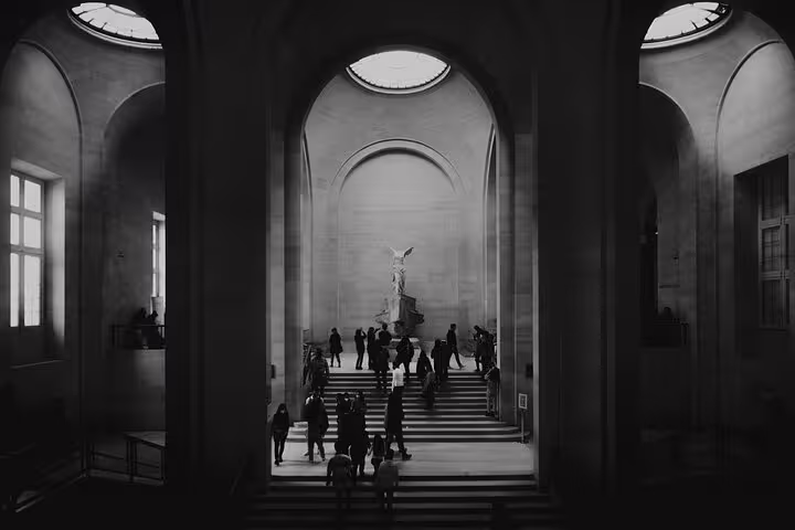 Visitors admire the Winged Victory of Samothrace in the Louvre's majestic staircase on the Mona Lisa tour.