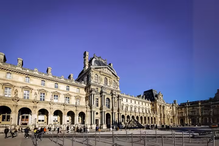Exterior of the Louvre Museum courtyard in Paris before a guided visit, with options for breakfast and Seine cruise