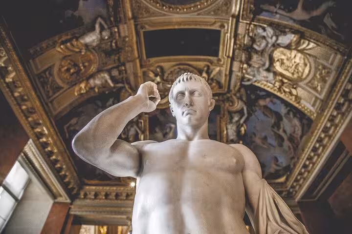 Marble statue inside the Louvre Museum on a private guided tour in Paris, ornate ceiling detail