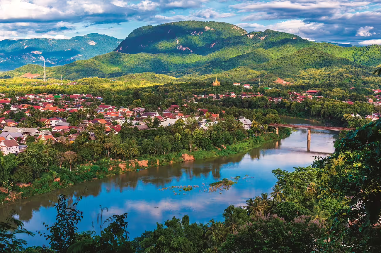 Panoramic view of Luang Prabang with Mekong River and lush mountains, capturing scenic beauty and cultural heritage.