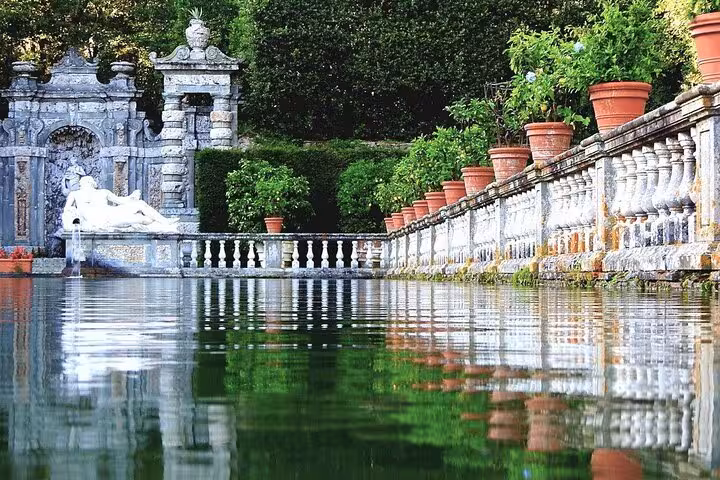 Elegant Italian garden in Lucca featuring a serene pond and classical statues.