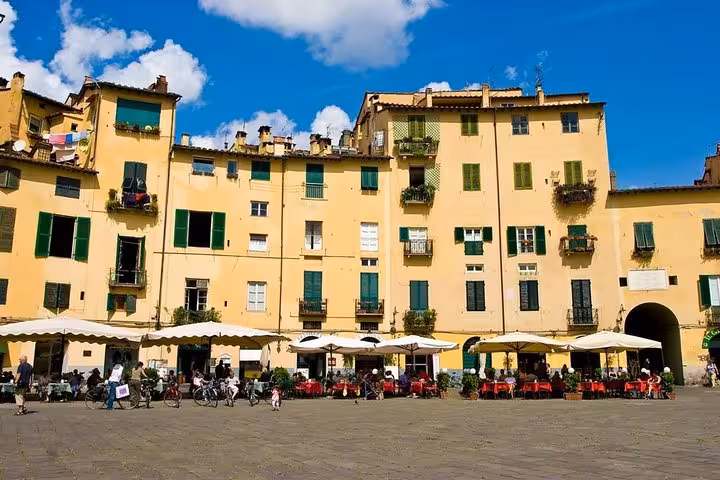 Charming cafes and vibrant buildings in Lucca's Piazza dell'Anfiteatro, a highlight of Pisa and Lucca day tour.