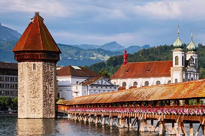 Charming view of Lucerne’s iconic Chapel Bridge and Water Tower against a backdrop of picturesque mountains.
