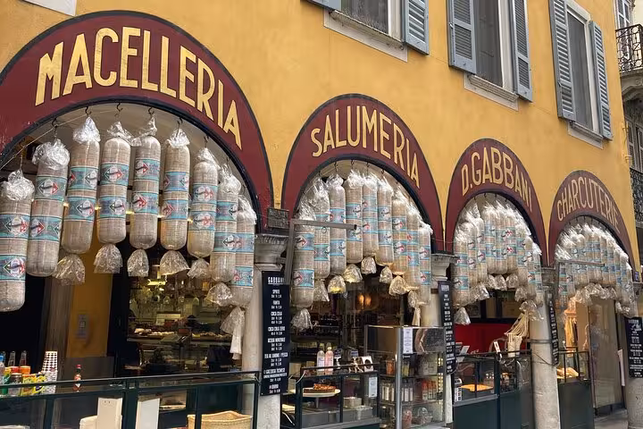 Traditional Lugano deli storefront with hanging salami and charcuterie, foodie stop on city tour walk