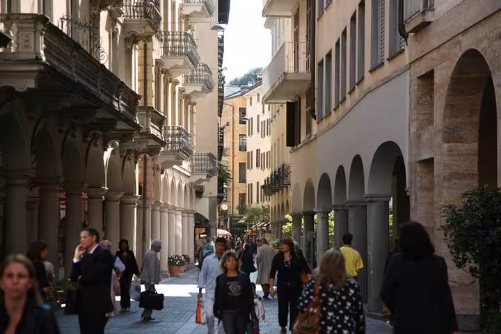 Pedestrian street in Lugano old town with arcades and historic facades, walking tour highlight in Ticino