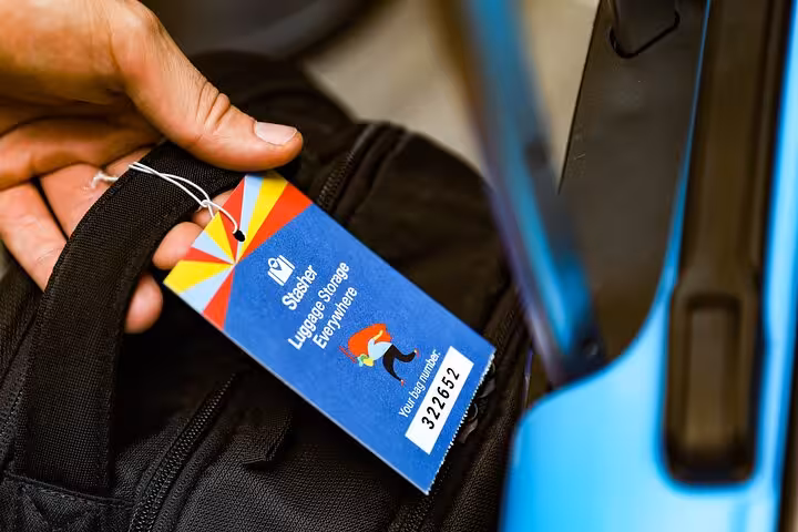 Hand holding luggage tag on suitcase for secure luggage storage in London, convenient bag drop service