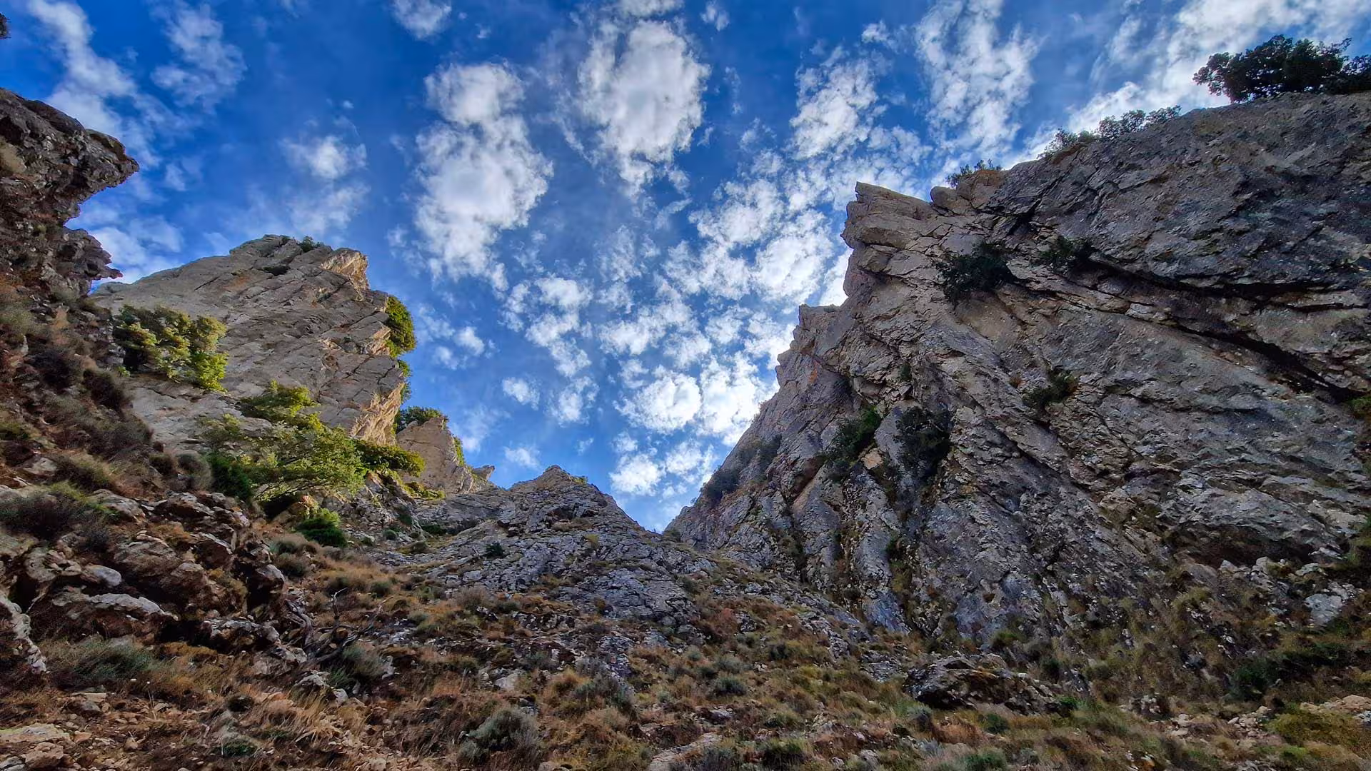View of dramatic cliffs under a vibrant blue sky with clouds on the Montalbo hiking trail, Lula adventure.