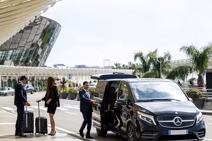 Driver welcomes travelers to a luxury van for Luxor Airport private transfer with luggage curbside pickup