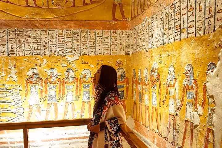 Traveler admiring colorful tomb paintings in Valley of the Kings on Luxor day trip from Hurghada