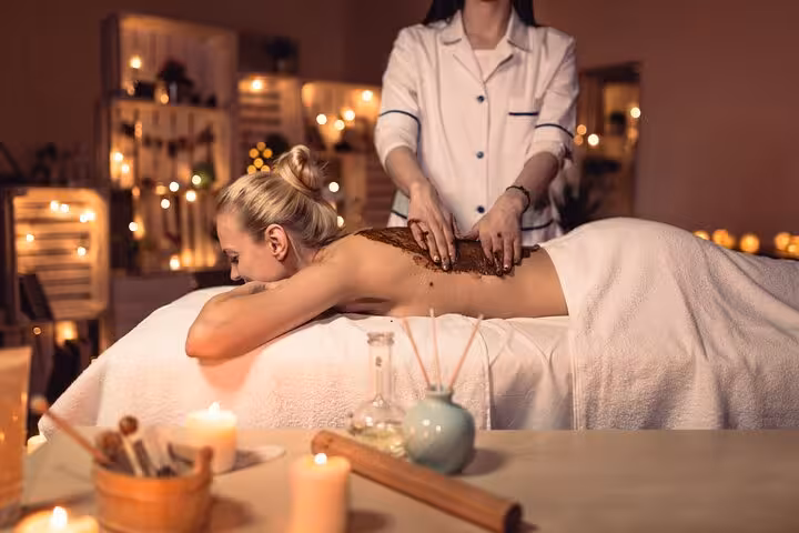 Therapist applying body scrub and massage in Luxor hammam spa, 2-hour relaxation package with candles