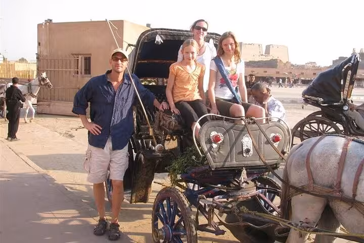 Family posing with Luxor horse carriage for a Nile Corniche city tour, classic ride and sightseeing stop
