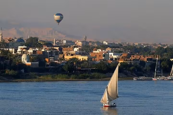 Luxor hot air balloon over Nile River with felucca sailboat at sunrise, VIP ride scenic city views