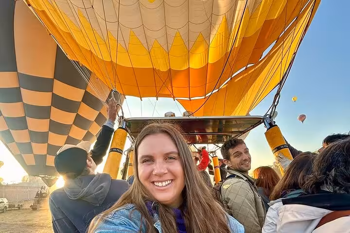Guests smiling in basket during Luxor sunrise hot air balloon flight, with hotel pickup and drop-off included