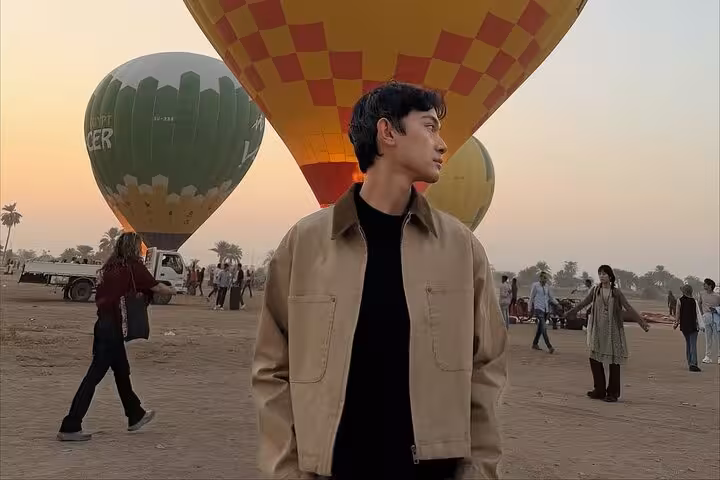 Traveler at Luxor hot air balloon takeoff area at sunrise, part of balloon ride with hotel pickup and drop-off