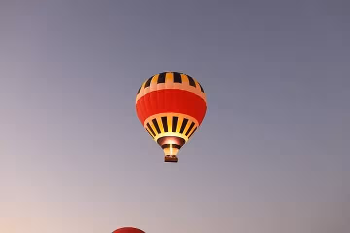 Colorful Luxor hot air balloon floating in clear dawn sky, VIP sunrise ride over ancient Egypt
