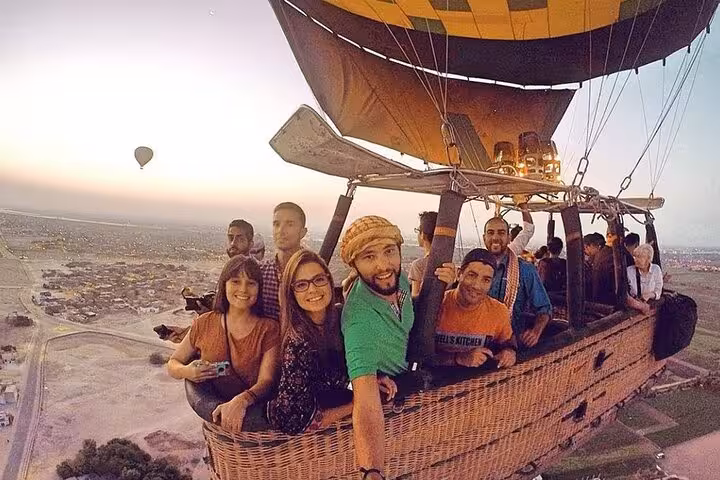 VIP Luxor hot air balloon basket with travelers at sunrise, panoramic views over Nile Valley and temples