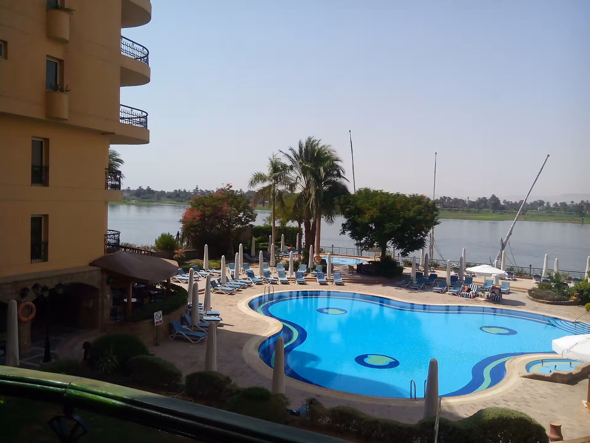 Luxurious hotel poolside view overlooking the Nile River in Luxor, offering a serene and relaxing atmosphere.
