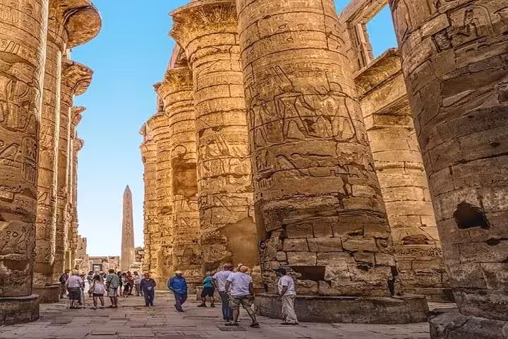Tour group walking between massive Karnak Temple columns, key Luxor East Bank highlight on full-day tour