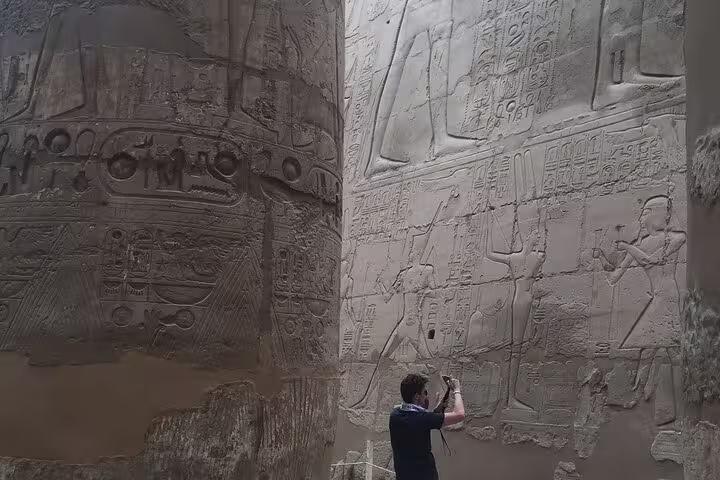 Traveler photographing ancient hieroglyphs at Karnak Temple, Luxor on private day trip from Hurghada