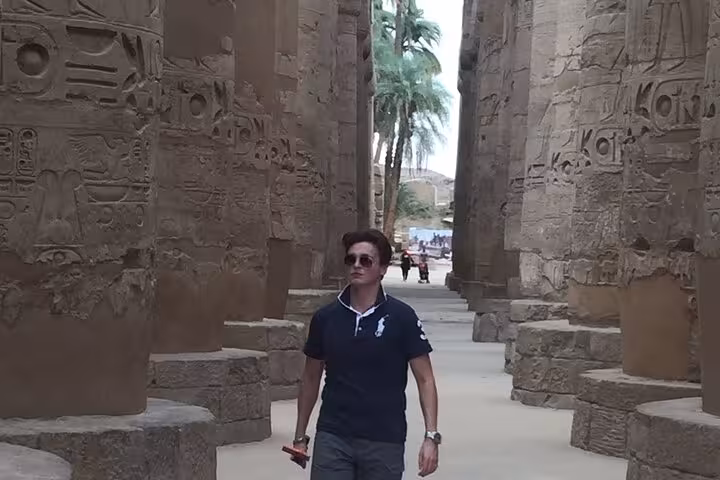Traveler walking between Karnak Temple columns with hieroglyphs on Luxor overday tour from Makadi Bay
