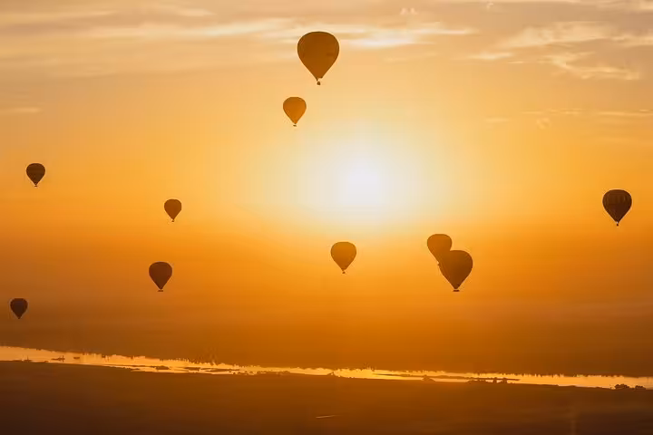 Hot air balloons silhouetted at sunrise over the Nile in Luxor, Egypt, on a dawn flight above ancient sites