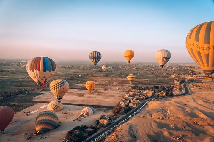 Sunrise view of multiple hot air balloons drifting above Luxor Nile River Valley and West Bank farmlands