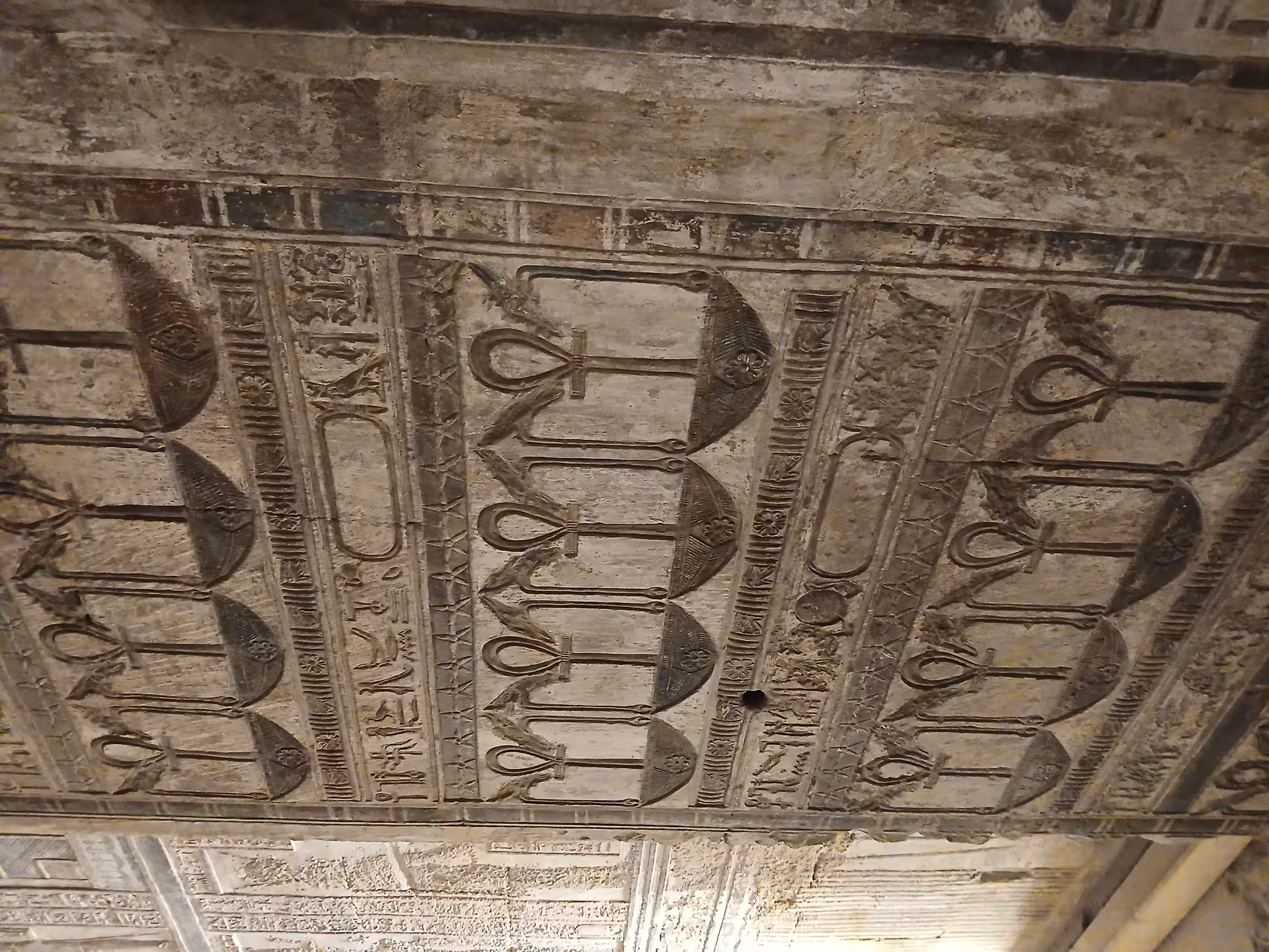 Intricate ancient Egyptian ceiling carvings with hieroglyphs and ankh symbols at a Luxor temple site.