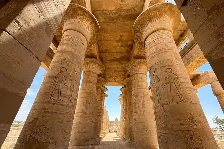 Majestic columns with hieroglyphs under a clear sky at a historic Luxor temple site included in the West Bank tour.