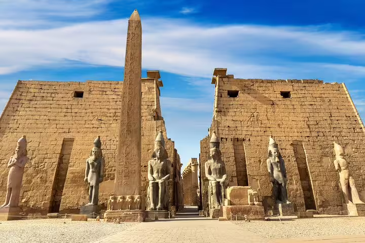 Luxor Temple courtyard with towering obelisk and seated statues, day trip by bus from Hurghada to Luxor