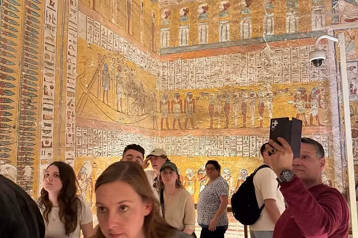 Tourists admire colorful hieroglyphics inside Luxor Temple, capturing the vibrant history of ancient Egypt.