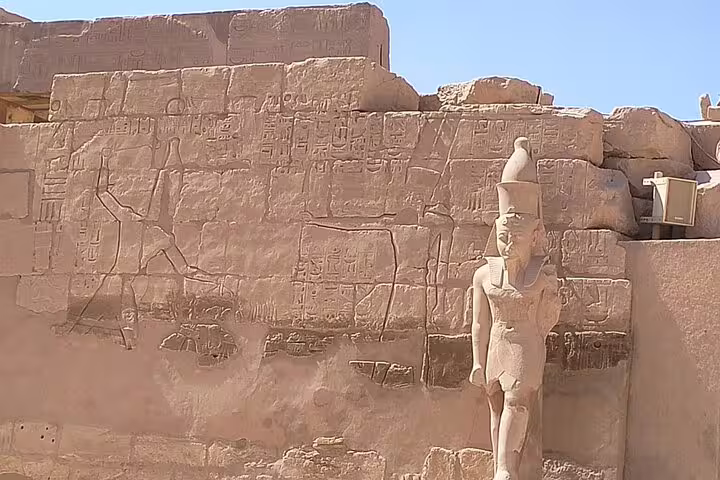 Ancient Luxor temple wall carvings and pharaoh statue, a highlight on 8-day Egypt Cairo pyramids Nile cruise