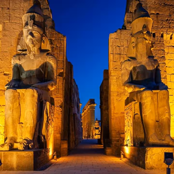 Illuminated statues at Luxor Temple entrance during twilight, highlighting ancient Egyptian architecture for night tours.