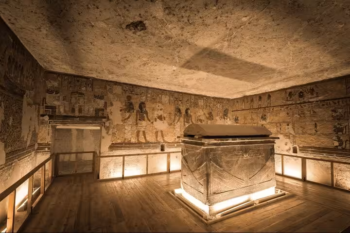 Illuminated ancient Egyptian tomb chamber with carved hieroglyphs and sarcophagus, Luxor West Bank tour