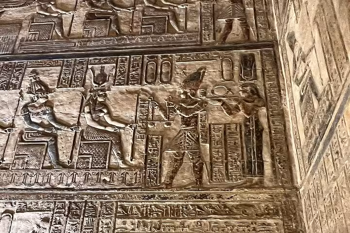Intricate ancient Egyptian carvings at Luxor's West Bank, showcasing historic hieroglyphics and deities.
