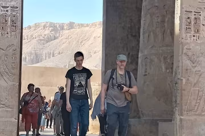 Tourists exploring the ancient carved pillars at the Luxor West Bank site.