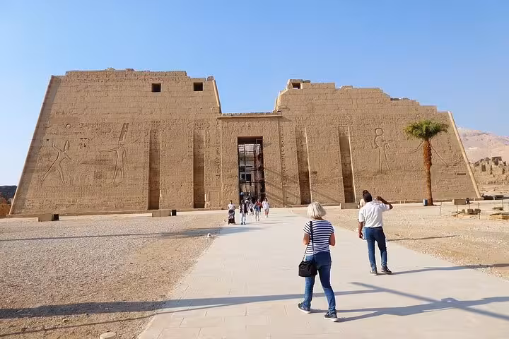 Visitors walking towards a grand temple entrance showcasing ancient carvings on a Luxor West Bank private day tour.
