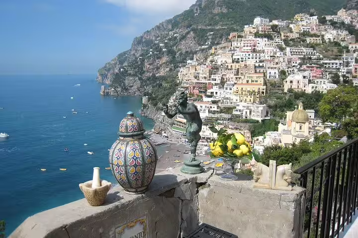 Luxury Amalfi Coast catamaran cruise view of Positano beach, colorful cliffside houses and lemon-decorated terrace in summer